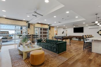 A living room with a green couch and a brown ottoman.